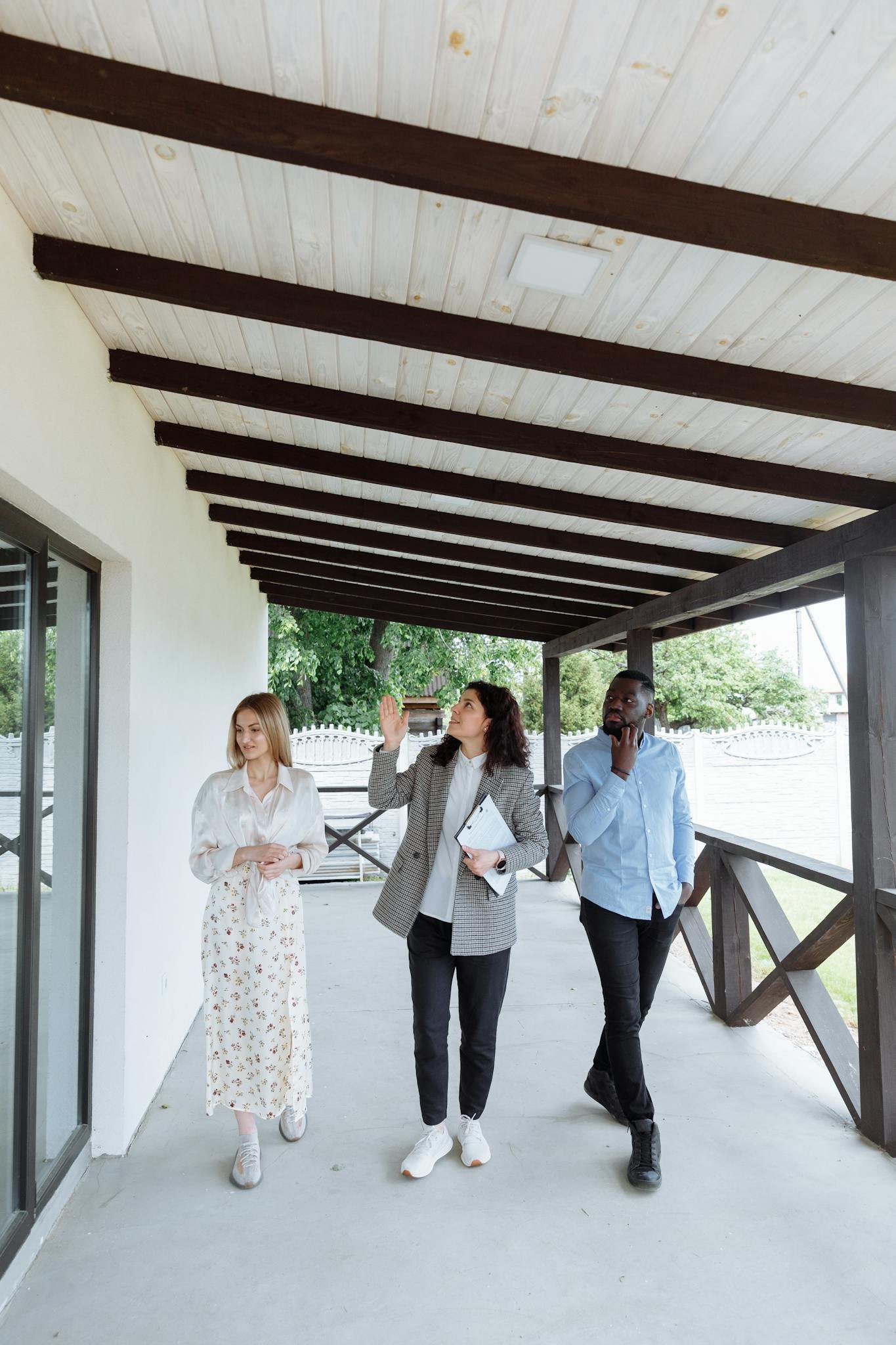 Real estate agent showing house to clients during walk-through on a porch.